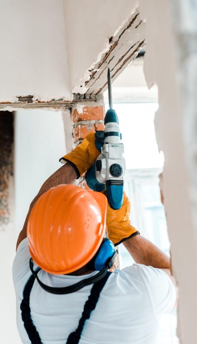 back-view-handyman-using-hammer-drill-wall
