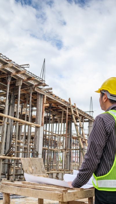 young business man professional engineer worker at the house building construction site with blueprint